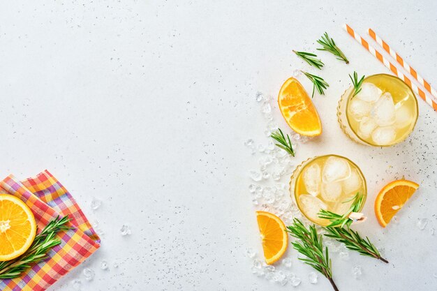 Orange juice or cocktail with rosemary and orange with ice in glass, cold summer lemonade