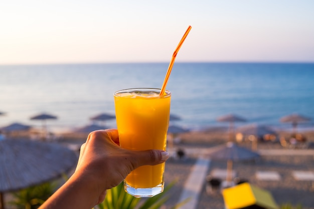 Orange juice in glass. cold drink. Hand with fresh tasty freshly juice of ripe oranges 