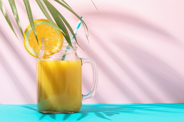 Orange juice in a glass on a colored background with copy space