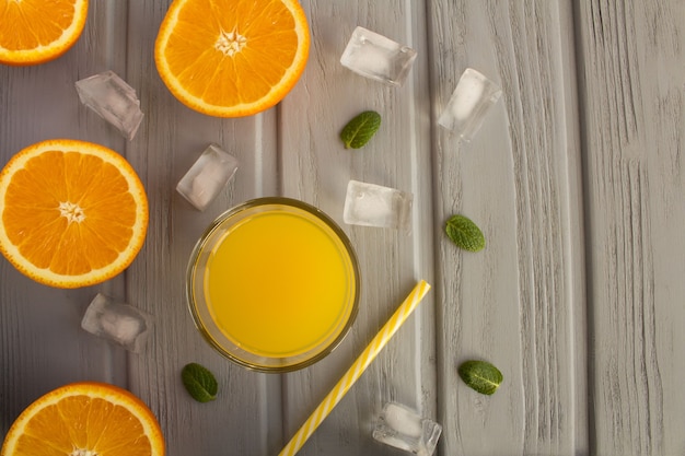 Orange juice in the glass  and halves of oranges on the grey wooden background.Top view.Copy space.