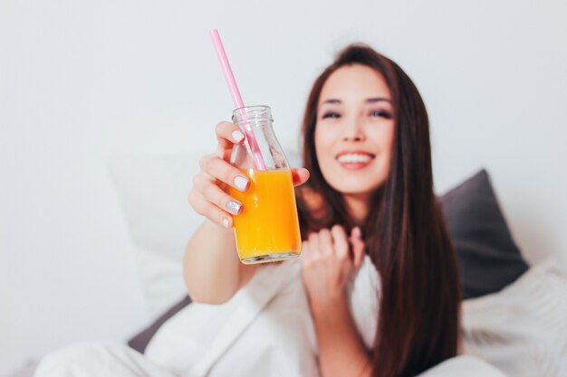 Orange juice in glass jar in hand of happy beautiful smiling asian girl young woman