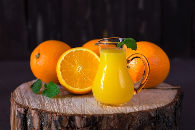 Orange juice in a glass jug on a wooden stump