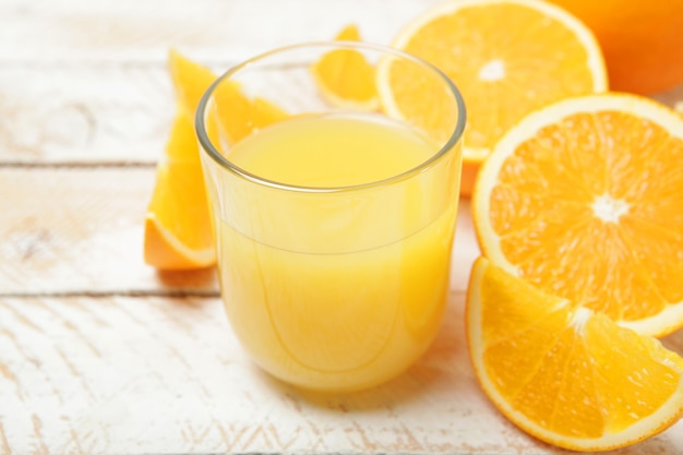 Апельсиновый сок в стакане апельсины и дольки апельсина на столе
