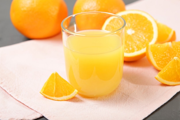 Orange juice in a glass oranges and orange slices on the table