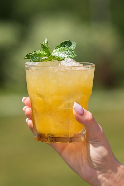 Orange juice and hand woman hand pour juice into a cocktail\
glass filled on natural background