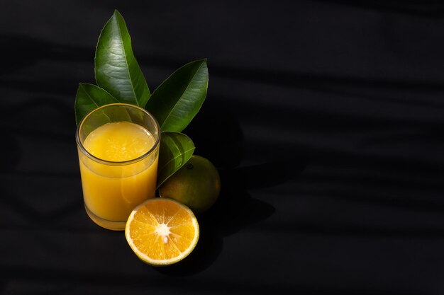 A Orange juice leaves and fruit with a black background and space for text on the right side