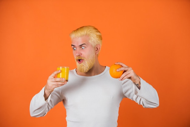 Orange juice man with orange fruit on orange background close up portrait young man holding sliced o