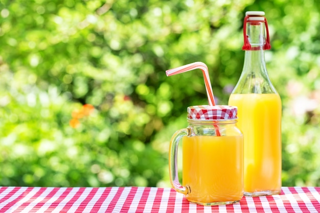 Orange juice in mason jars and bottle on wooden table