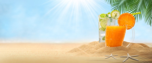 Orange juice and mojito drink, Empty sand with hat and mojito drink on landscape beach blurred background