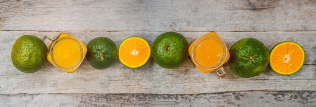 Orange juice and oranges with green peel on a wooden background