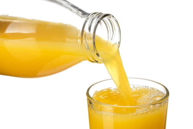 Orange juice pouring from the jar into a glass on a white background