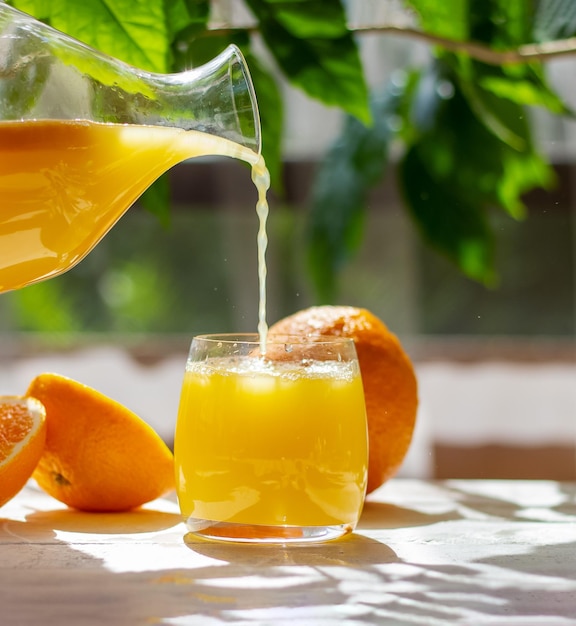 Orange juice pouring from pitcher into glass Healthy citrus drink Summer freshness concept