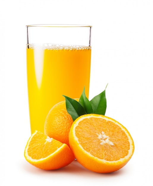 Orange juice pouring into glass and oranges with leaves