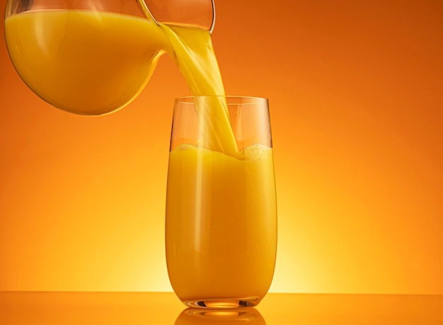 Orange juice pouring into glass with splash