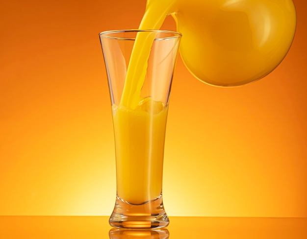 Orange juice pouring into glass with splash