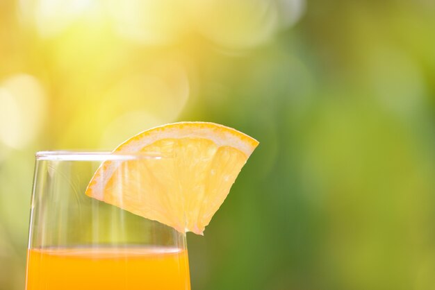 Orange juice with piece orange fruit on glass with nature green summer