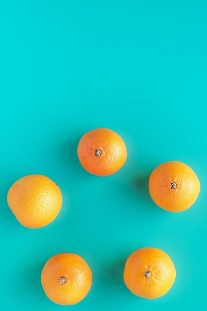Orange juicy tangerines on a turquoise background. Circle with citrus fruits.