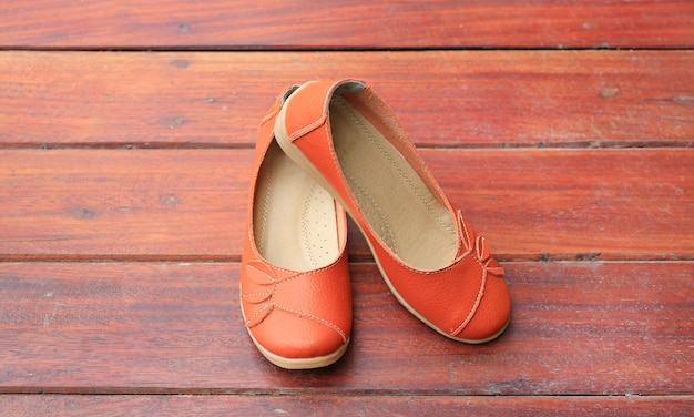 Orange leather female shoes on wood