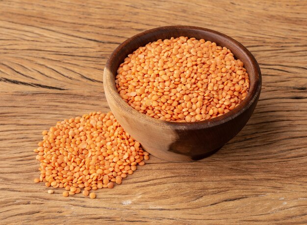 Orange lentil in a bowl over wooden table.