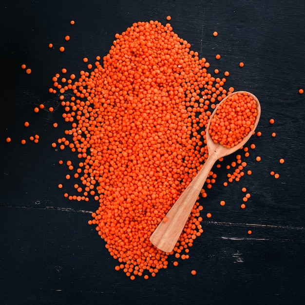 Orange lentils in a spoon On a wooden background Top view Copy space