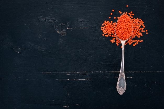 Orange lentils in a spoon On a wooden background Top view Copy space