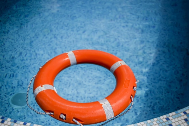Orange life buoy in the pool orange lifebuoy on a background of water summer vacation concept