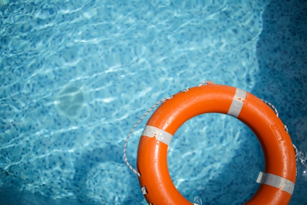 orange life buoy in the pool orange lifebuoy on a background of water Summer vacation concept