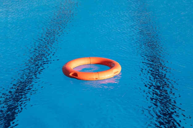 Orange lifebuoy floating on a pool