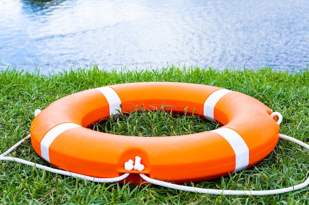 An orange lifebuoy on the grass.