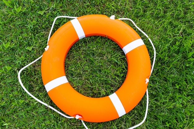 An orange lifebuoy on the grass.