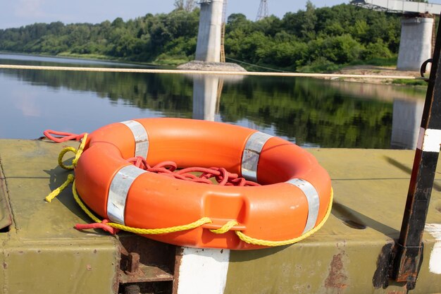 Photo orange lifebuoy ring on the riverbank closeup