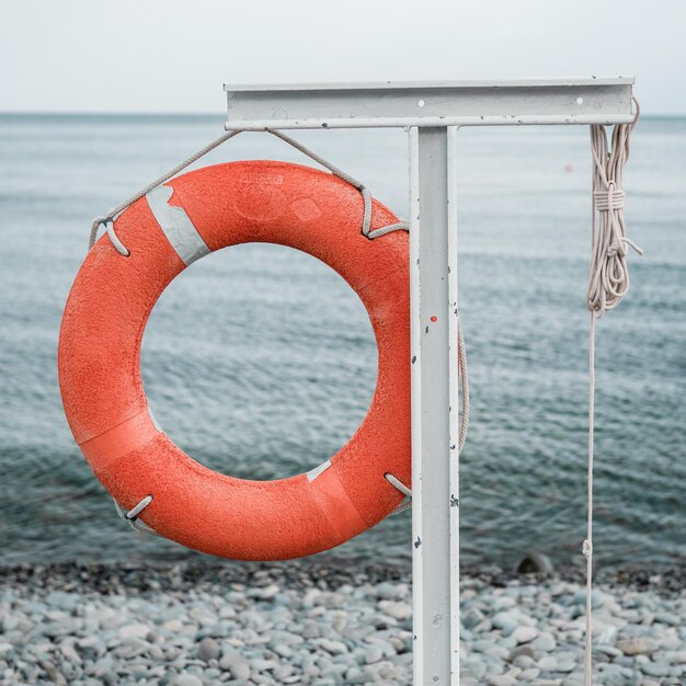 Orange lifebuoy on the sea coast on cloudy day