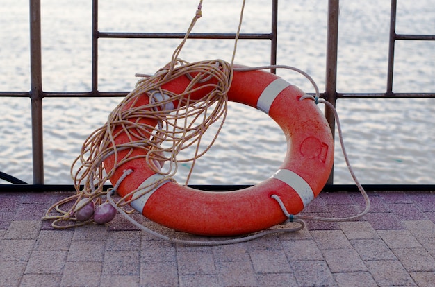 Orange lifebuoy with rope on the pier