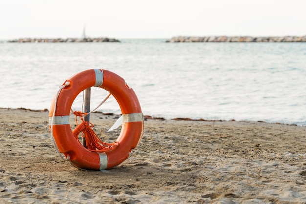 Оранжевый спасательный круг или спасательный буй на песчаном пляже