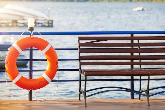 Orange lifesaver and wooden bench by the beach