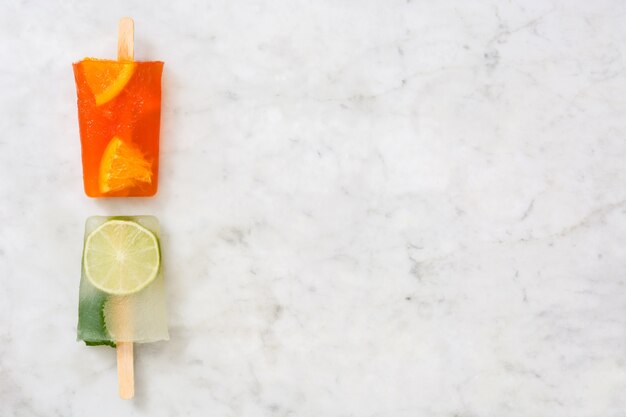 Orange and lime popsicles fruit on marble