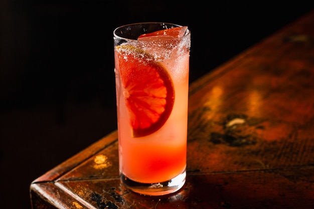 Un cocktail arancione basso abv in un bicchiere highball riempito di ghiaccio e guarnito con un pezzo di arancia