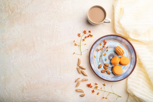 Orange macarons or macaroons cakes with cup of coffee on a white