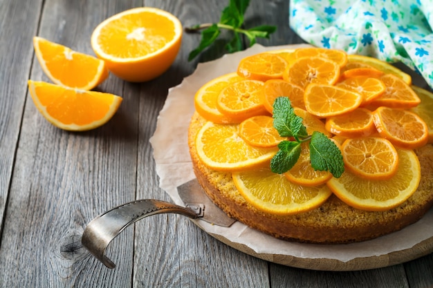 Foto torta all'arancia e mandarino con polenta, capovolta sul vecchio piano di legno. messa a fuoco selettiva.