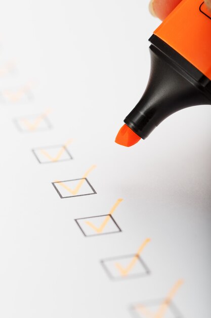 Фото Оранжевый маркер с маркерами на листе контрольного списка