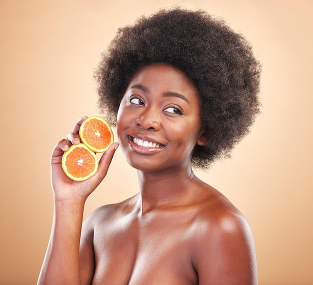 Orange natural skincare and woman on studio background for healthy cosmetics vegan benefits or nutrition Happy african beauty model thinking of citrus fruits for vitamin c diet or eco dermatology