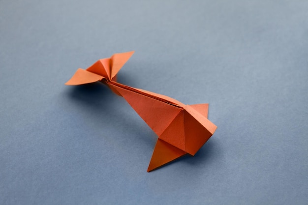 Orange paper fish origami isolated on a grey background