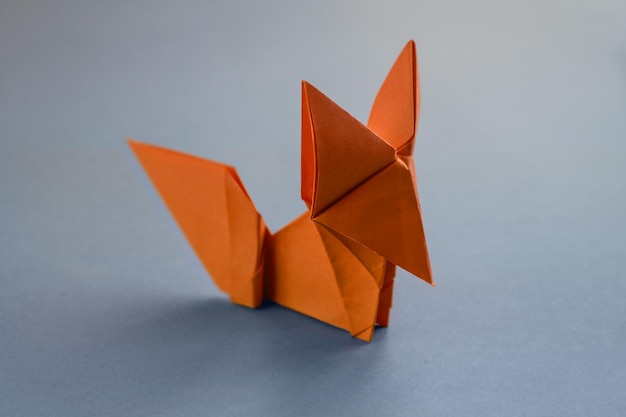 Foto origami di volpe di carta arancione isolati su sfondo grigio