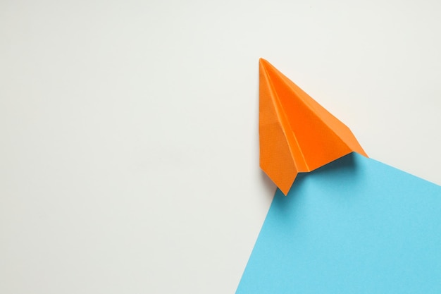 Orange paper plane on white blue background