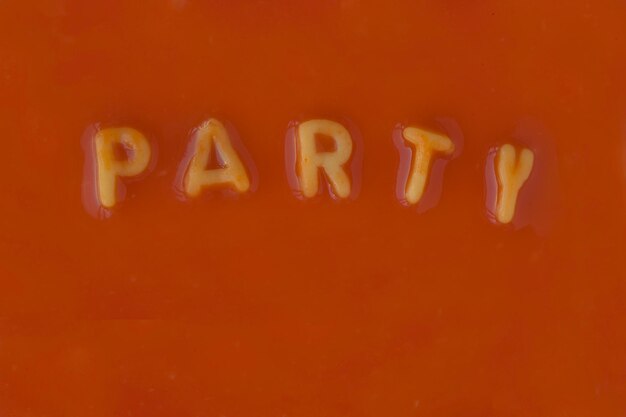 사진 오렌지색 파스타 글자 들 이 은 토마토 소스 에서 '파티'라는 단어 를 표기 하고 있다.