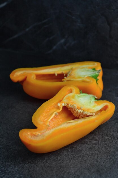 orange pepper lies on a black table