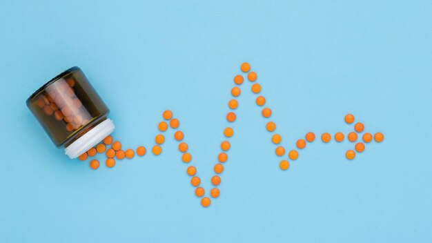 Orange pills are poured out of the bottle in the form of a cardiogram