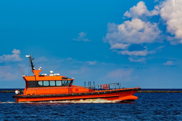 Оранжевый лоцманский катер движется по реке в Европе. Спасательная служба