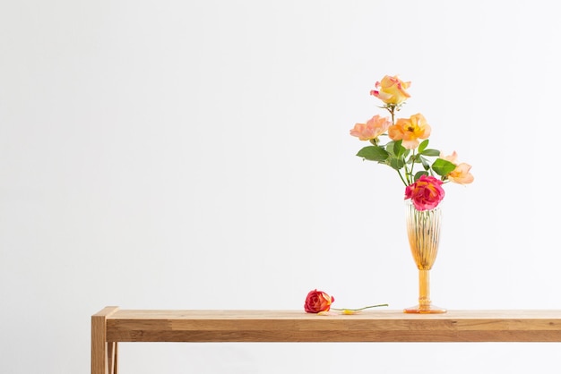 Orange and pink roses in glass vase in white interior