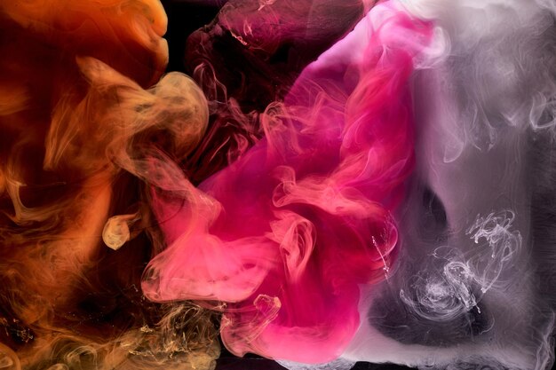 Orange pink smoke on black ink background colorful fog abstract swirling touch ocean sea acrylic paint pigment underwater